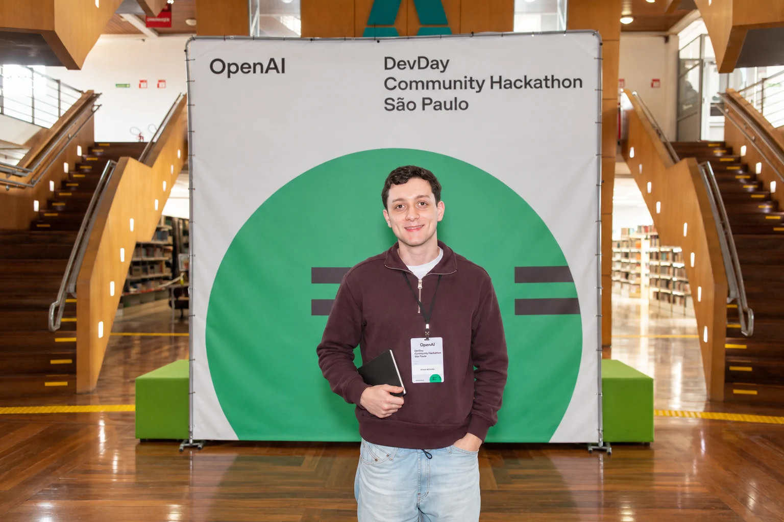 Ryan Moura em frente ao painel do DevDay Community Hackathon em São Paulo.